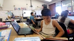 FILE - Angel Urquia wears a tank top as he studies under whirling ceiling fans that provide little relief in a hot classroom without air conditioning, at Fryberger Elementary School in Westminster, Calif., Thursday, Oct. 20, 2016. (AP Photo/Nick Ut)