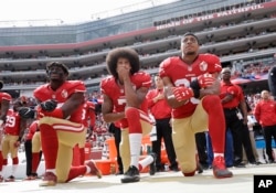 FILE - From left, San Francisco 49ers outside linebacker Eli Harold, quarterback Colin Kaepernick and safety Eric Reid kneel during the national anthem before an NFL football game against the Dallas Cowboys in Santa Clara, California, Oct. 2, 2016.