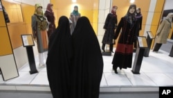 FILE - Head-to-toe veiled Iranian women look at mannequins in a women's dress show in Tehran, Iran, March 3, 2012. 