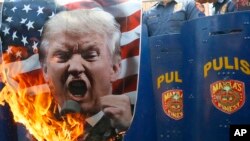 Protesters burn a portrait of U.S. President Donald Trump in front of riot police during a rally in front of the U.S. Embassy in Manila, Philippines, Feb. 4, 2017. The protesters were criticizing Trump's anti-immigration stance.