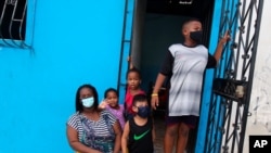 Una familias usa máscaras para protegerse contra la propagación del nuevo coronavirus mientras esperan afuera de su casa en el vecindario de Cristo del Consuelo para recibir alimentos del gobierno local de Guayaquil, Ecuador.