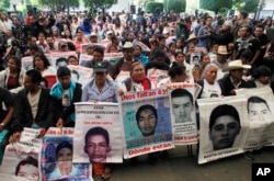 FILE - Relatives of 43 missing students missing since they were taken by local police in September 2014 hold photos of their loved ones, April 24, 2016.