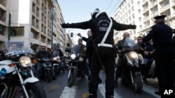 A traffic policeman tries to stop public transport employees as they ride on motorcycles during a protest in Athens, Feb 11, 2011