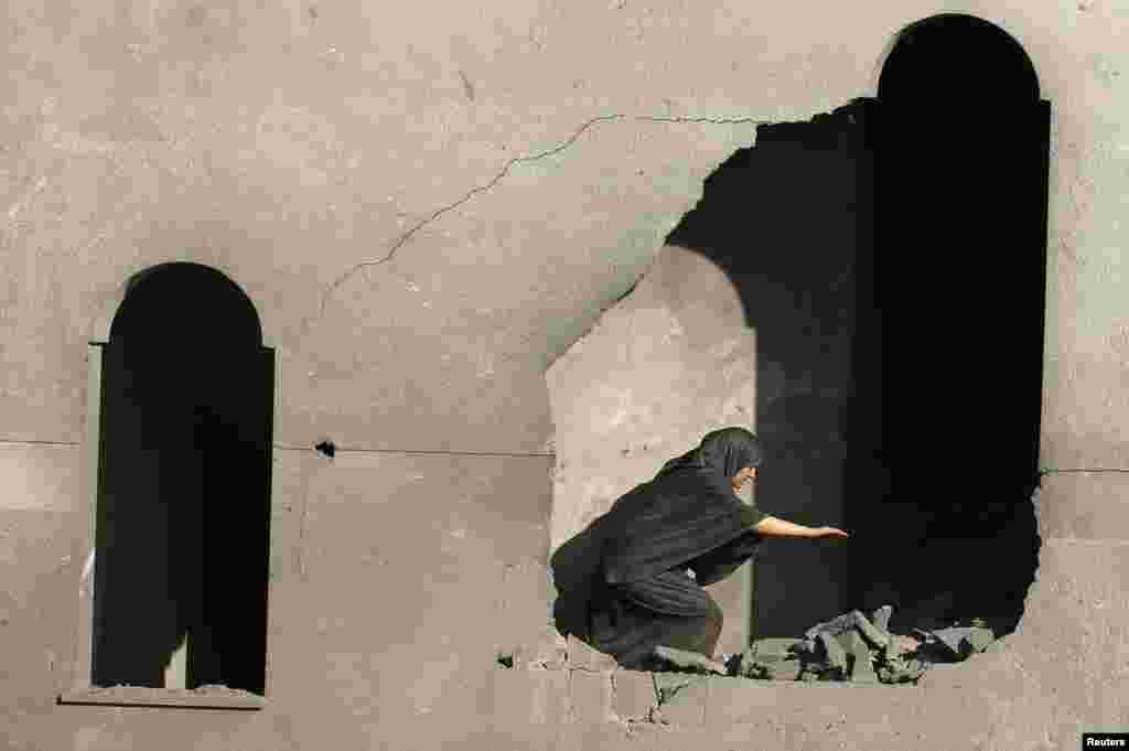 A Palestinian woman inspects her house that witnesses said was damaged during an Israeli airstrike in Gaza City.