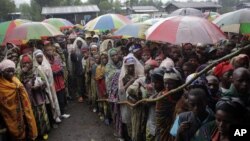 FILE - Internally displaced Congolese men and women wait for World Food Program energy biscuits to be distributed in Kibati, north of Goma, eastern DRC, Aug. 8, 2012.