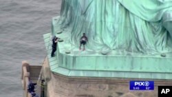 Polisi berbicara dengan seorang perempuan yang memanjat bagian bawah Patung Liberty, New York, pada Hari Kemerdekaan, Rabu, 4 Juli 2018. 