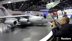 FILE - A foreign visitor takes a photo of a model of Y-20 military transporter aircraft at Aviation Industry Corporation of China (AVIC)'s booth at the Aviation Expo China 2015, in Beijing, Sept. 16, 2015.