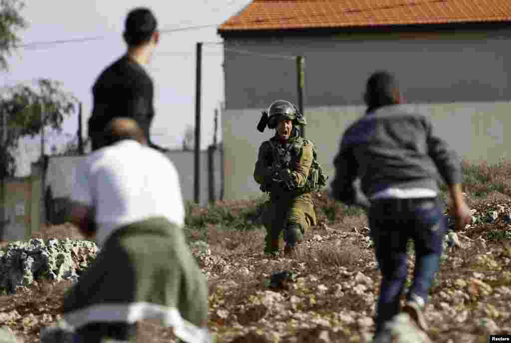 An Israeli soldier shouts as he holds his weapon in front of Palestinians during clashes in Jalazoun refugee camp near the West Bank city of Ramallah. Clashes broke between stone-throwing protesters and Israeli soldiers, two days after Muhammad Mubarak, 21, a resident of the refugee camp was killed by Israeli soldiers who said he had opened fire on their position near a Jewish settlement in the occupied West Bank.