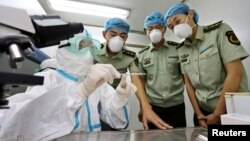 A health inspection and quarantine researcher (L) demonstrates to customs policemen the symptoms of Ebola, at a laboratory at an airport in Qingdao, Shandong province, Aug. 11, 2014.