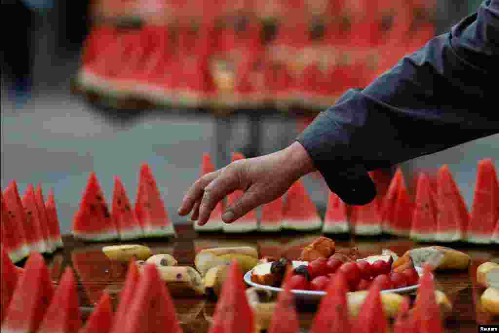 A man reaches for food as Muslims gather before breaking fast on the first Friday of the holy fasting month of Ramadan at the historic Niujie Mosque in Beijing, China.