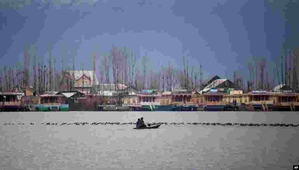 Kashmiri Muslims cross the Dal Lake on a small boat as migratory birds move on the water surface in Srinagar, India.
