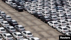 FILE - A man walks among cars which are ready for export at the port of Taipei, northern Taiwan, April 16, 2014. 