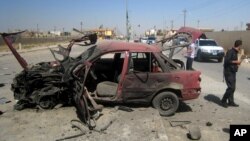 People inspect the site of a car bomb attack on cars lined up at a gas station in the oil rich city of Kirkuk, in northern Iraq, July 10, 2014. 