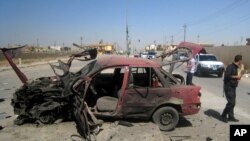 People inspect the site of a car bomb attack on cars lined up at a gas station in the oil rich city of Kirkuk, in northern Iraq, July 10, 2014.