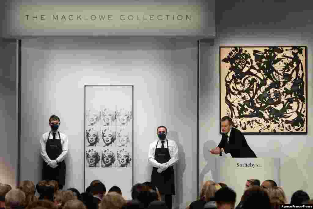 Sotheby&#39;s auctioneer Oliver Barker leads an auction of The Macklowe Collection, alongside Andy Warhol&#39;s &quot;Nine Marilyns&quot; (L), which sold for $47,373,000, and Jackson Pollock&#39;s &quot;Number 17, 1951&quot; (R), at Sotheby&#39;s in New York, Nov. 15, 2021.