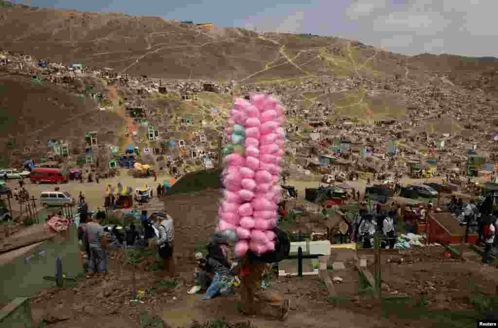 A street vendor sells cotton candy as people visit tombs of relatives and friends at &#39;Nueva Esperanza&#39; (New Hope) cemetery during the Day of the Dead celebrations in Villa Maria del Triunfo on the outskirts of Lima, Peru, Nov. 1, 2016.