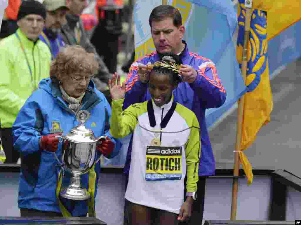 Walikota Boston Marty Walsh menaruh mahkota di kepala Caroline Rotich dari Kenya, pemenang divisi perempuan di Boston Marathon (20/4). ​(AP/Elise Amendola)