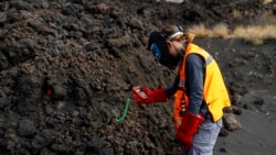 A scientist with the Canary Islands' volcanology institute, Involcan, measures the temperature of a lava, or melted rock from a volcano, flow on the Canary island of La Palma, Spain, on October 30, 2021. (AP Photo/Emilio Morenatti)