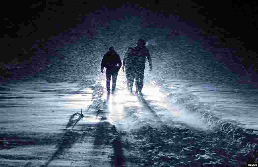 Orang-orang berjalan melalui badai salju untuk menyeburkan diri mereka ke air sedingin es dalam perayaan Epifani Ortodoks atau Hari Raya Penampakan Tuhan di danau yang airnya beku di desa Dubrovichi di luar Ryazan, Rusia.