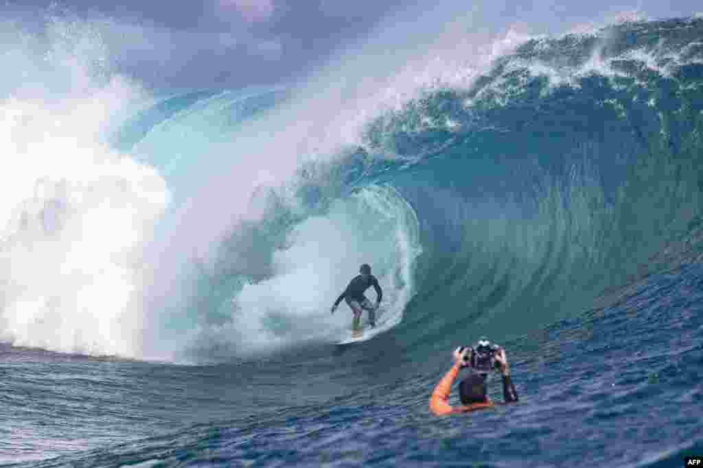 Surfer Benji Brand from Hawaii, U.S., practices while a photographer taking pictures ahead of the Tahiti pro surfing trial at the famous break Teahupoo in Tahiti, French Polynesia.