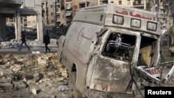 Residents walk past a damaged emergency vehicle in Aleppo, Syria, January 1, 2013.