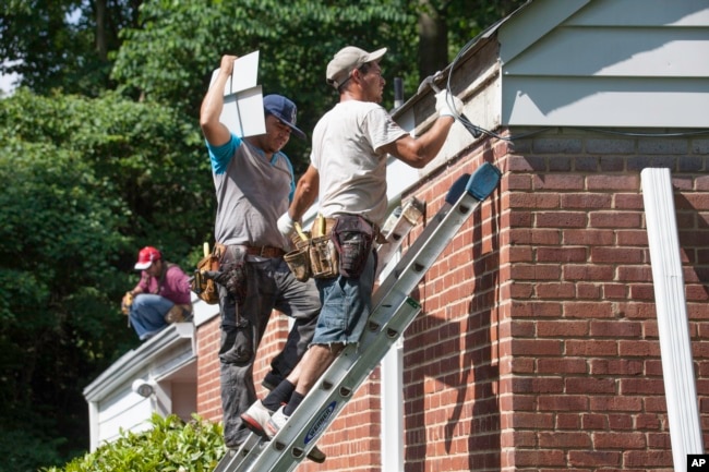 These workers repair the roof of a house in the U.S. state of Virginia, June 2014. (AP Photo/J. Scott Applewhite)