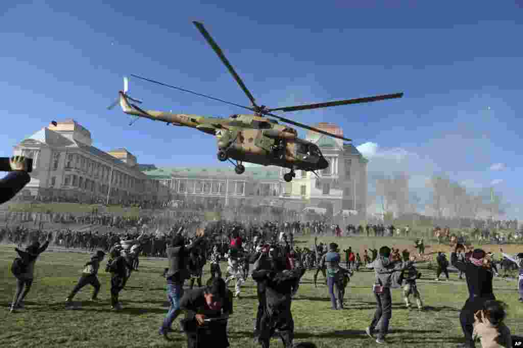 A military helicopter flies over people during the Afghan Security Forces Exhibition, at the Darul Aman Palace in Kabul.