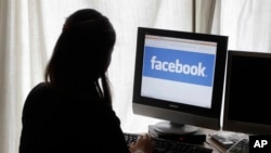 FILE - A girl checks Facebook on her computer in Palo Alto, California.
