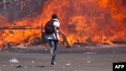 FILE - Zimbabwe's opposition supporters set up a burning barricade as they clash with police during a protest for electoral reforms, Aug. 26, 2016 in Harare, Zimbabwe.