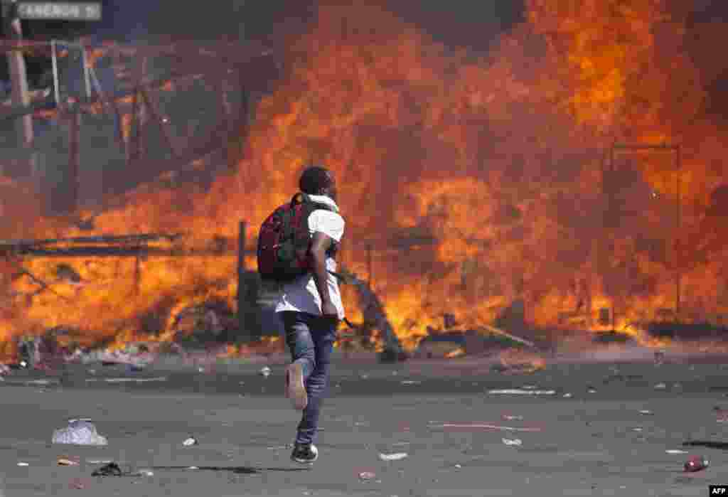 Zimbabwe&#39;s opposition supporters set up a burning barricade as they clash with police during a protest for electoral reforms in Harare.