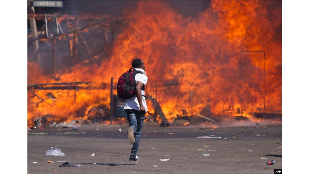 FILE - Zimbabwe's opposition supporters set up a burning barricade as they clash with police during a protest for electoral reforms, Aug. 26, 2016 in Harare, Zimbabwe.
