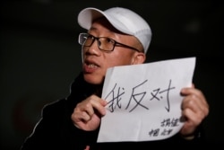 2018年2月28日，在北京接受路透社采访时，中国维权人士胡佳手持标语“我反对”。（2018年2月28日）