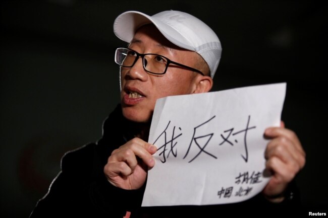 2018年2月28日，在北京接受路透社採訪時，中國維權人士胡佳手持標語「我反對」。（2018年2月28日）