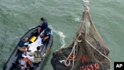 Bags containing dead bodies of the passengers of AirAsia Flight 8501 are lifted to Indonesian navy vessel KRI Banda Aceh at sea off the coast of Pangkalan Bun, Indonesia, Saturday, Jan. 3, 2015.