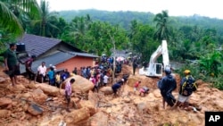 Sri Lankans watch military rescue efforts at the site of a landslide at Bellana village in Kalutara district, Sri Lanka, May 26, 2017. Mudslides and floods triggered by heavy rains in Sri Lanka killed dozens and left many more missing. 