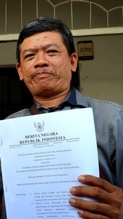 Tri Wahyu menunjukkan salinan Permen pedoman penanganan benturan kepentingan di lingkungan Kemenkum HAM. (Foto:VOA/Nurhadi)