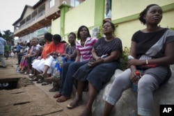 FILE - Voters wait three hours after biometric identification machines had broken down, halting voting at a polling station, in Accra, Ghana, Dec. 7, 2012.