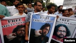 Pakistani journalists carry posters with the picture of local reporter Faizullah Khan, who was detained and imprisoned in Afghanistan, during a protest for his release outside the press club in Karachi, July 15, 2014.