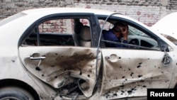 A man sits in his car which is damaged after a bomb attack in Quetta, April 24, 2013.