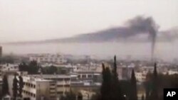 This image from amateur video made available by Shaam News Network, purports to show black smoke rising in the air in Homs, Syria, Thursday, Feb. 16, 2012.