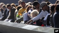 Family members view the names of their relatives etched into the 9/11 Memorial during the commemoration of the 11th anniversary of the terrorist attacks on the World Trade Center in New York, September 11, 2012.