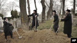 Rabbis take a break from the reburial remains of Holocaust victims found in a mass grave in northern Romania, at the Jewish cemetery in Iasi, Romania, Monday, April 4, 2011