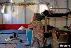 FILE - Syrian refugee Walaa, 26, sits inside her family's tent at the Souda municipality-run camp on the island of Chios, Greece, Sept. 7, 2016.