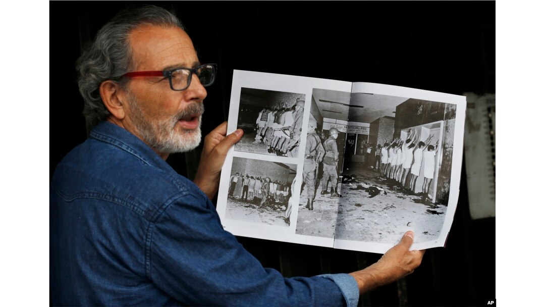 In this Sept. 18, 2018 photo, Enrique Espinosa shows a magazine photo in which he and other demonstrators are being detained by armed soldiers during the Tlatelolco massacre in Mexico City.