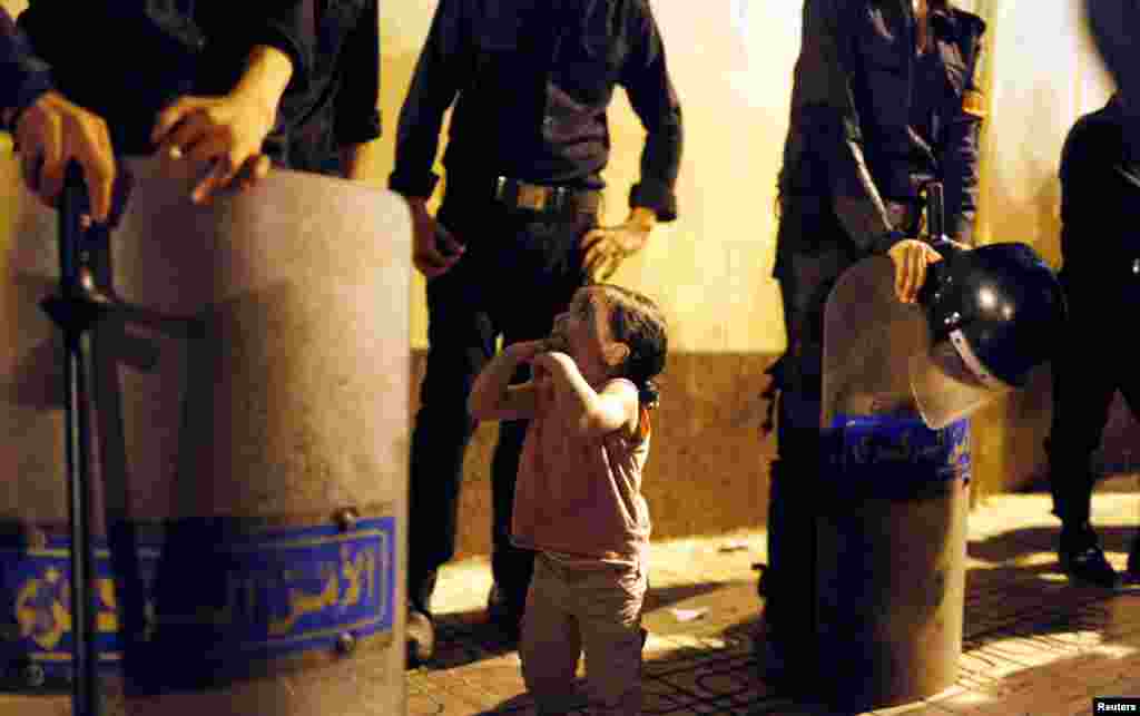 A child belonging to Morsi supporters looks at members of riot police guarding the presidential palace.