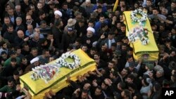 Shi'ite militant group Hezbollah's fighters and supporters carry the coffins of a father and son, wrapped in a Hezbollah flag, during their funeral procession in the southern town of Ghaziyeh, Lebanon, Jan. 21, 2015.