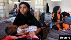 Una niña yemenita sostiene a un bebé en un refugio temporal en el puerto de Bosasso, Somalia.