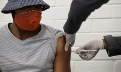 FILE - A volunteer receives an injection from a medical worker during the country's first human clinical trial for a potential vaccine against the novel coronavirus, at Baragwanath Hospital in Soweto, South Africa, June 24, 2020.