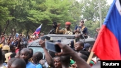 FILE - Burkina Faso's self-declared new leader Ibrahim Traore is welcomed by supporters holding Russian's flags as he arrives at the national television standing in an armoured vehicle in Ouagadougou, Burkina Faso October 2, 2022. 