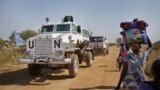 FILE - In this Monday, Dec. 30, 2013 file photo, a United Nations armored vehicle passes displaced people walking towards the U.N. Protection of Civilians camp in Malakal, South Sudan. 